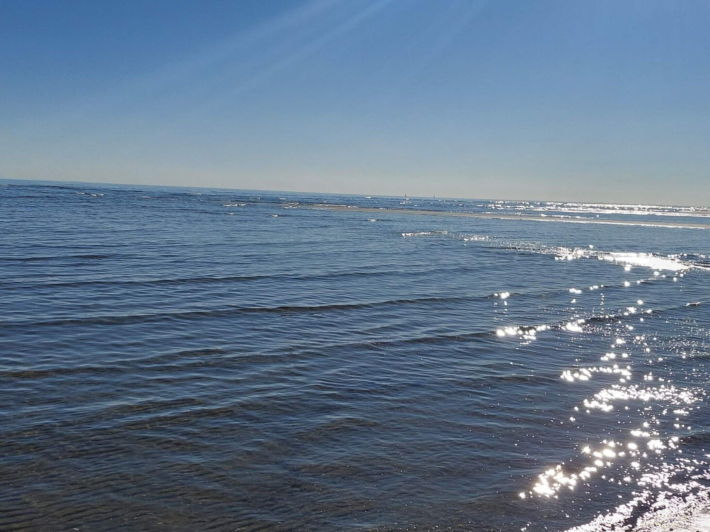 A calm sea with gentle waves and a clear sky.