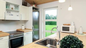 A modern kitchen with stainless steel appliances, a wooden countertop, and a view of a green lawn through a large window.