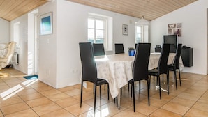 En spiseplads med et bord dækket til fire personer, omgivet af sorte stole, et hvidt borddække og et træloft.