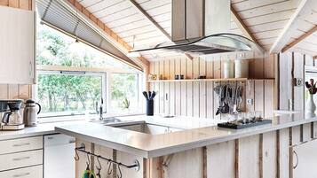 A modern kitchen with wooden cabinetry, a large island, and a window providing natural light.