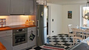 A kitchen with grey cabinets, a stainless steel refrigerator, a wooden countertop, and a checkered floor. - Holiday Home in Häradsbäck (Häradsbäck)