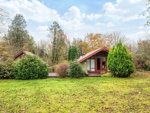 A two-story house with a red roof, surrounded by a well-maintained lawn and various trees. - 4 Person Holiday Home in Oksbol (Oksbol)