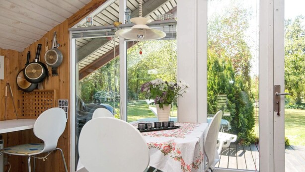 Une cuisine avec une table dressée pour deux personnes, un barbecue et une vue sur un jardin.