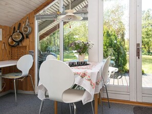 A kitchen with a table set for two, a grill, and a view of a garden.