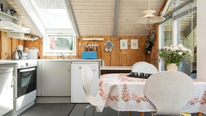 Une cuisine compacte équipée d’un réfrigérateur, d’une cuisinière et d’un évier. On y trouve une table à manger avec des chaises et un petit réfrigérateur.