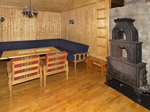 A wooden room with a bench, a table, and a fireplace.
