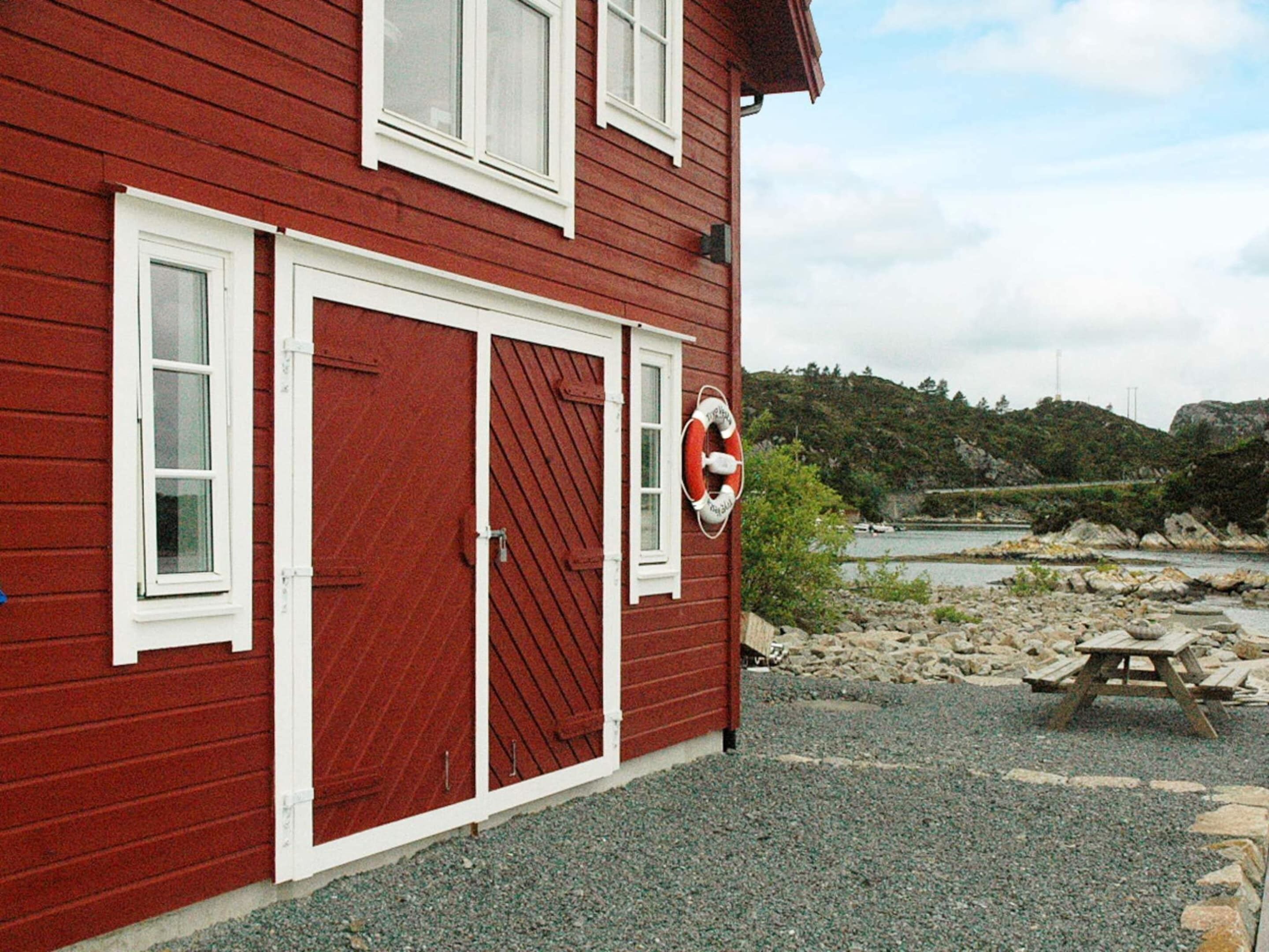 A red building with white-framed windows and a lifebuoy attached to the wall.
