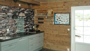 A kitchen with a stone backsplash, wooden cabinets, a black countertop, and a fish-themed wall hanging. - Holiday Home in Urangsvåg (Bomlo)