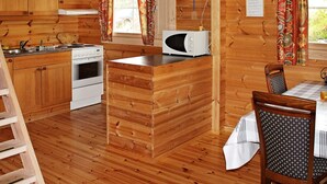 Een houten hut van binnen met een keuken, eethoek en een klein kookeiland.