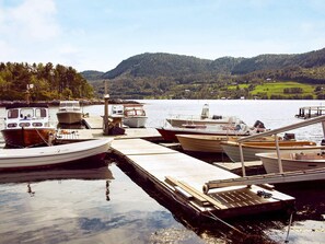 A dock with several boats moored, surrounded by calm water and a forested hillside.