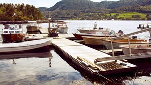 A dock with several boats moored, surrounded by a calm lake and forested hills. - 5 Person Holiday Home in Vagland (Heim)