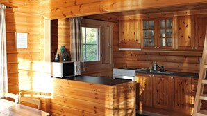 A wooden cabin kitchen with a central island, a dining table, and a window. - 5 Person Holiday Home in Vagland (Heim)