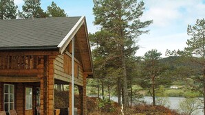 A wooden cabin with a porch, a view of a lake, and surrounding trees. - 5 Person Holiday Home in Vagland (Heim)