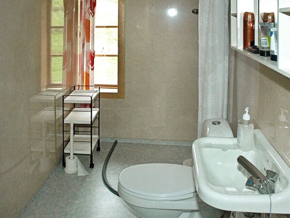 A bathroom with a toilet, sink, and a window with curtains. - 5 Person Holiday Home in Vagland (Heim)