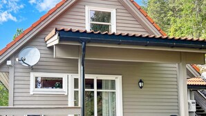 Ein Haus mit Giebeldach, Satellitenschüssel und einer Veranda mit Geländer.