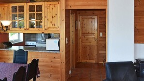 Ein Holzblockhaus-Interieur mit Küchenbereich, Esstisch und Stühlen.