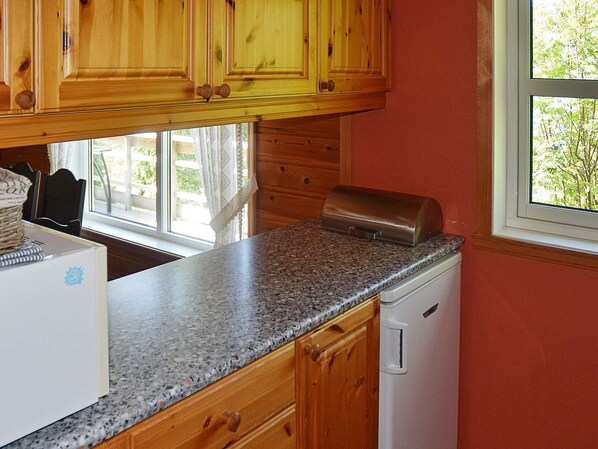 A kitchen with wooden cabinets, a granite countertop, a toaster, and a window with a view of greenery. - 4 Star Holiday Home in Leikanger (Sogndal)