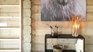 Pared de madera con un retrato enmarco de un carnero, un adorno y una pequeña mesa con una vela y ramas.