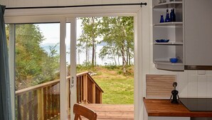 A modern kitchen with a wooden table and chairs, a built-in oven, and a view of a deck and trees. - 4 Person Holiday Home in Bjoa (Vindafjord)
