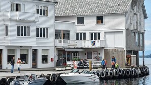 A waterfront building with a restaurant on the ground floor, a dock with boats, and a pier extending into the water. - 4 Person Holiday Home in Bjoa (Vindafjord)