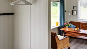 A room with a wooden bench, a chair, a table with a vase of flowers, and a window with curtains. - 4 Person Holiday Home in Bjoa (Vindafjord)