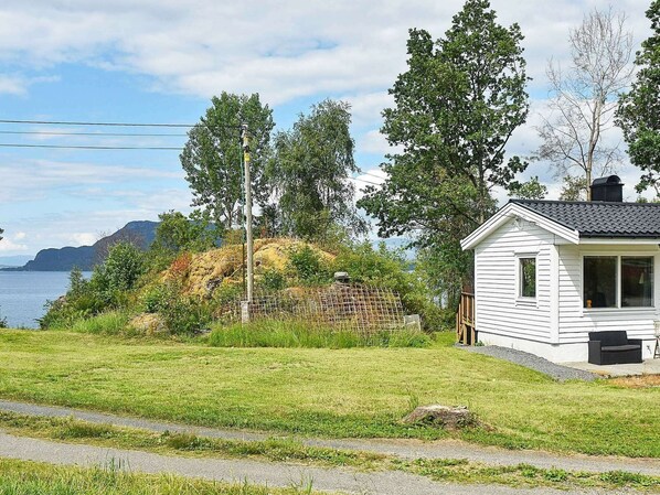 A small white cabin with a stone wall and a view of the water. - 4 Person Holiday Home in Bjoa (Vindafjord)