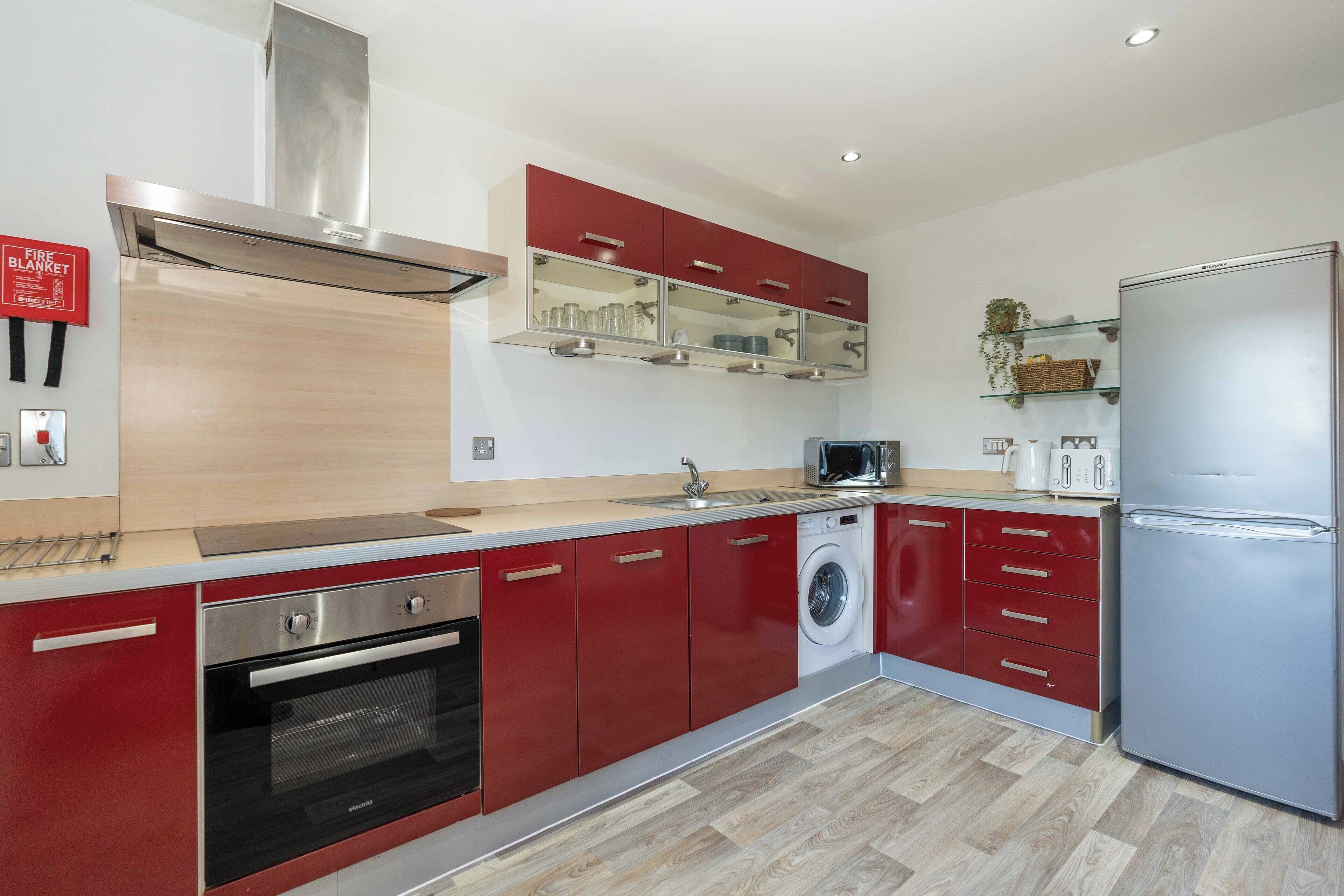 Una cocina moderna con electrodomésticos de acero inoxidable, armarios colorados y un microondas integrado.