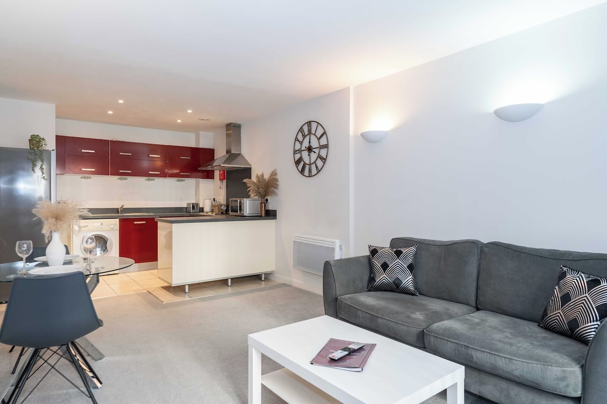 Un salon moderne avec un canapé gris, une table basse blanche et un coin repas comprenant une table et des chaises.