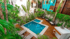 A rooftop pool with wooden deck and lounge chairs, surrounded by lush tropical plants. - Ocean Front Villa @ Private Beach in Tulum. Snorkel, Kayak, Paddleboard Included (Tulum)