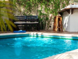 Relax by the serene pool surrounded by lush greenery and a wooden deck.