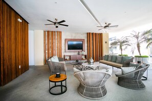 A modern lounge area with a flat-screen TV, ceiling fans, and a sofa set.