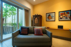A living room with a sofa, two cushions, a cabinet, and two framed artworks on the wall.