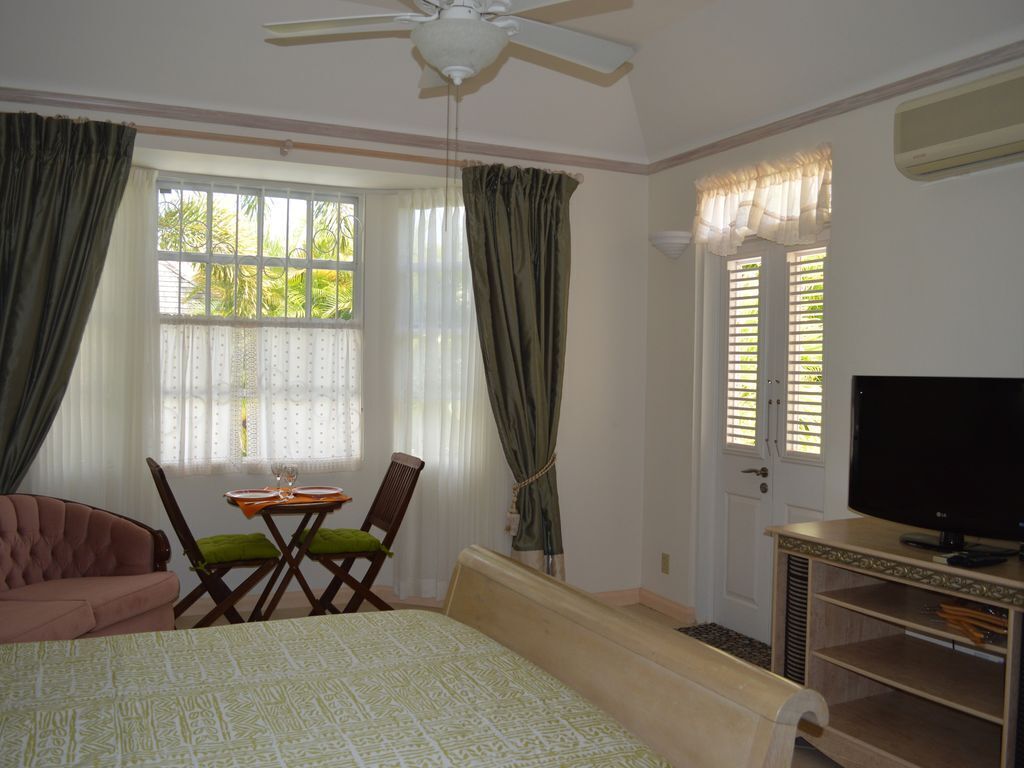 A bedroom with a bed, a desk with a chair, a television, and a window with curtains.