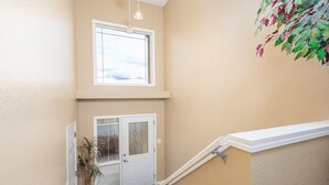 A staircase with a white handrail, a door with a glass panel, and a potted plant on the left. - Paradise Canyon Golf Resort - Luxury Condo U409 (Lethbridge)