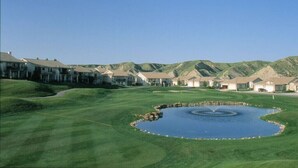 A golf course with a pond, surrounded by residential buildings.