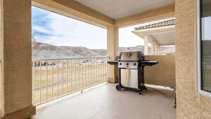 Un balcon avec un barbecue, une vue sur un paysage vallonné et un espace abrité avec un toit en tuiles.