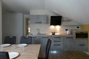Una cucina moderna con mobili grigi, un tavolo da pranzo in legno e un forno integrato.
