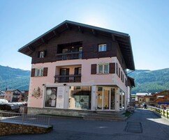 Un edificio a più piani con un ristorante al piano terra, caratterizzato da ampie finestre e un balcone.