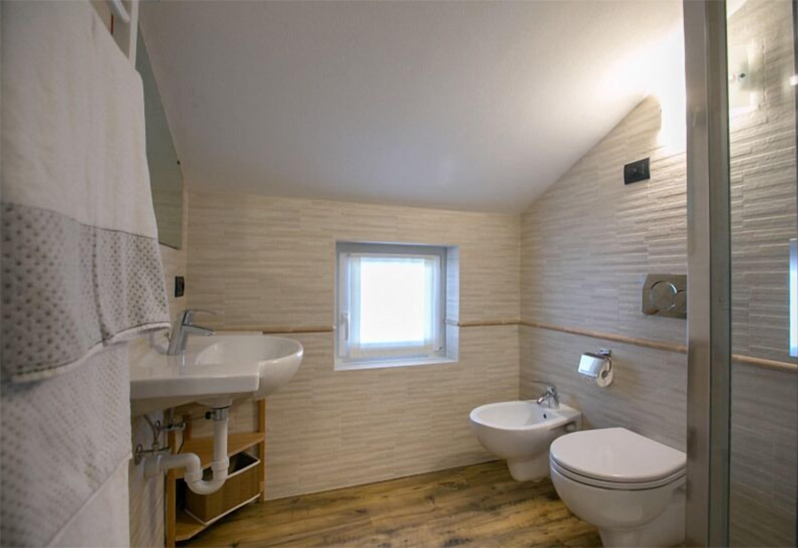 A compact bathroom with a sink, bidet, and toilet.