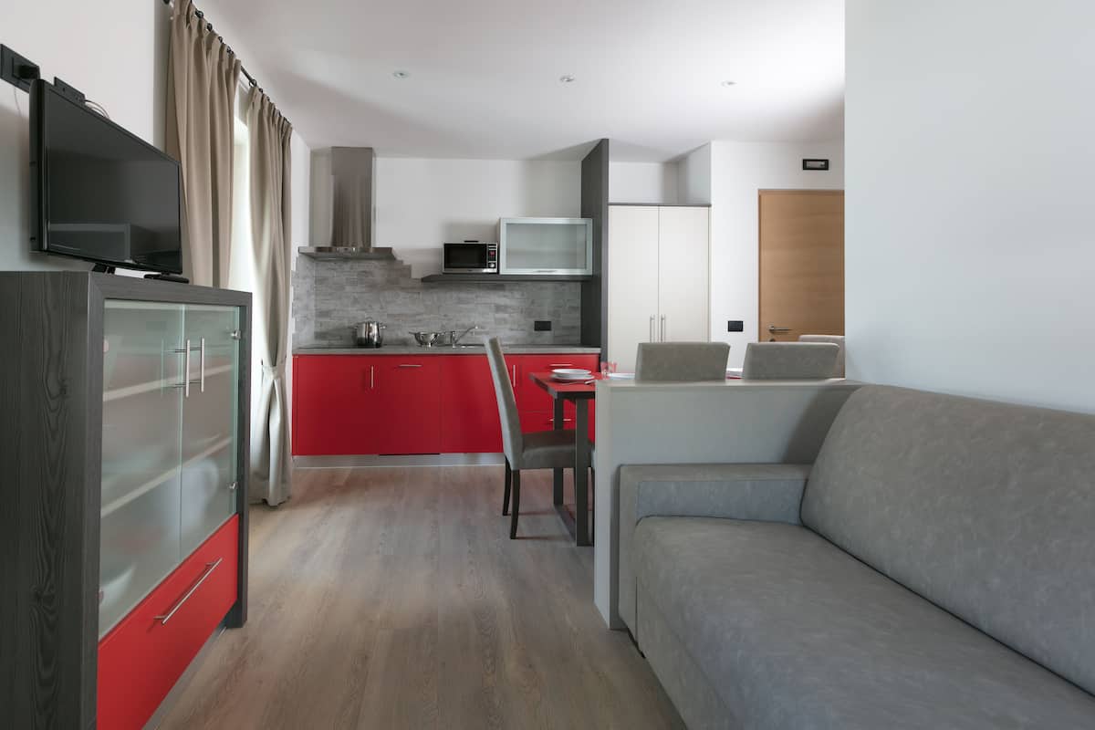 A modern kitchen with red cabinets, a microwave, and a dining area with a table and chairs.