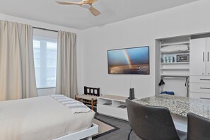 A hotel room with a bed, a desk with a computer, a TV mounted on the wall, and a wardrobe. - Heart of South Beach Ocean Drive Studio - Steps to Beach + Art Deco District (Miami Beach)