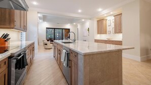 Una cocina moderna con una isla grande, armarios de madera y electrodomésticos de acero inoxidable.