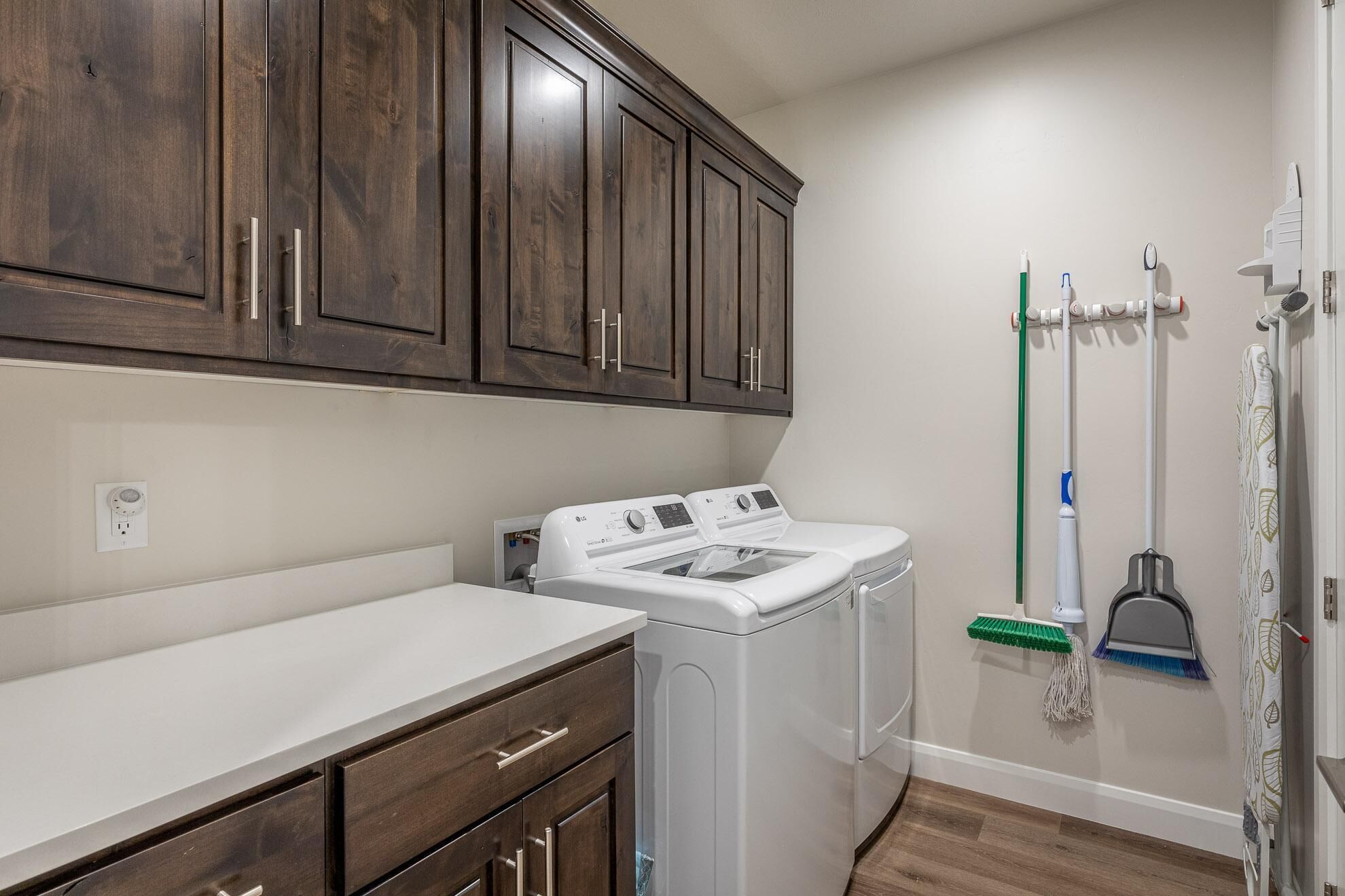 A laundry area with a washer and dryer, wooden cabinets, and a mop rack.