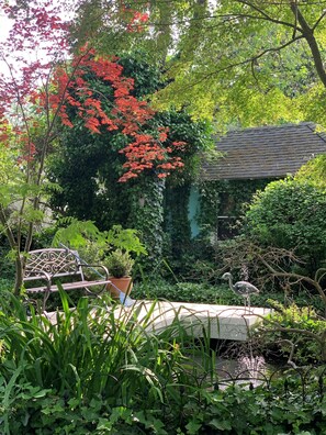 Un jardín con una fuente, un banco y un comedero para pájaros.