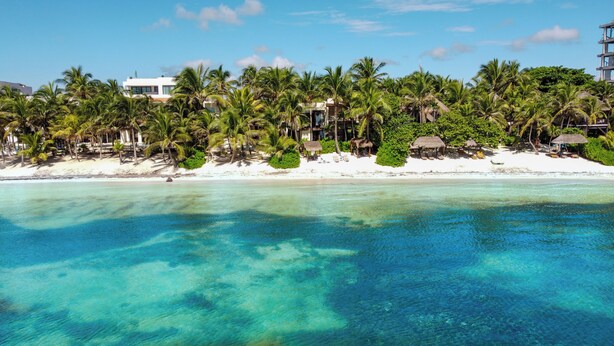 Een strandresort met helder turquoise water, palmbomen en witte zandstranden.