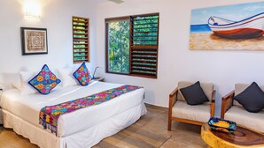 Een slaapkamer met een bed, een bank, een houten salontafel, een raam met zonwering en een schilderij van een boot aan de muur.