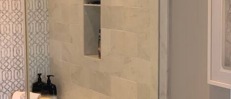 Un baño con zona de ducha, tocador con espejo y inodoro.