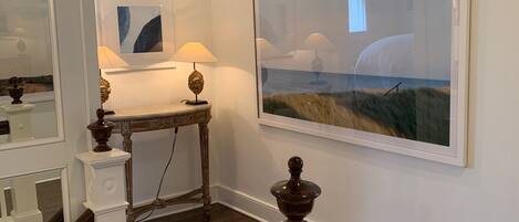 A staircase with a wooden handrail, a small table with a lamp, and a framed picture on the wall.