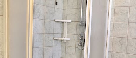 A glass-enclosed shower with a white sink and a handheld showerhead.