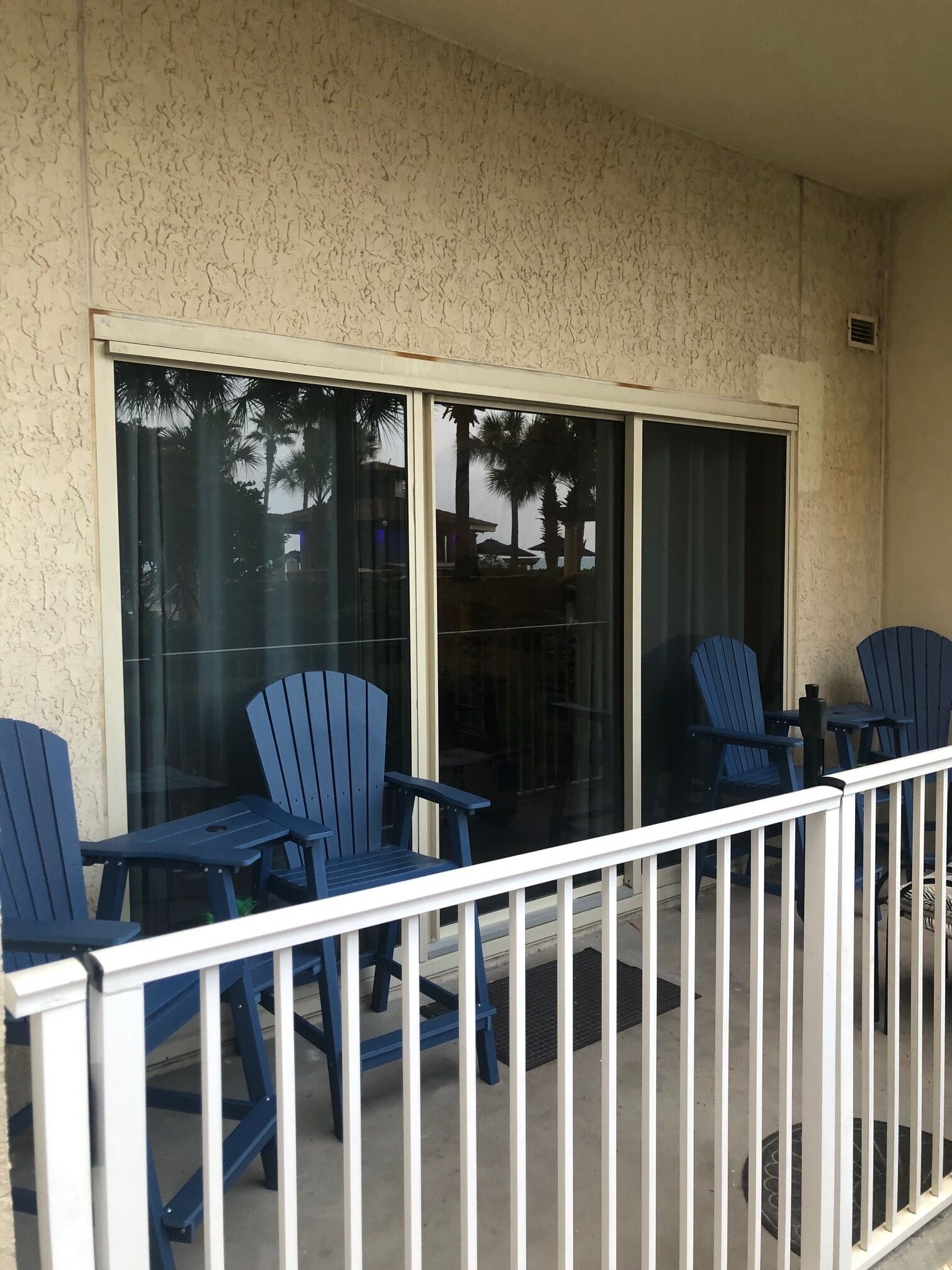 A balcony with blue chairs and a white railing.